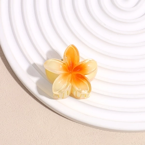 Detail view of orange frangipani hair claw clip with gradient petals on a display plate