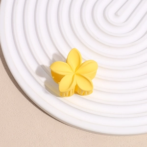 Détail de la pince à cheveux fleur jaune mate avec dents de maintien sur fond clair