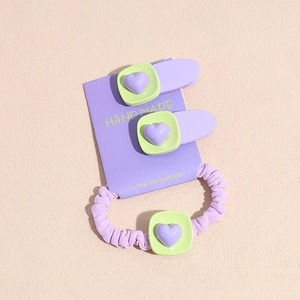 Détail d'un ensemble de chouchou et barrettes cœur violet sur une carte support