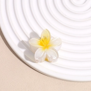 Detail of plumeria hair claw clip with yellow gradient on a white ceramic tray