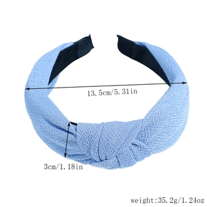Close-up of light blue knotted headband with fabric texture, 13.5cm width and 35.2g weight