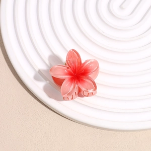 Detailed close-up of a gradient pink frangipani flower hair claw on a ceramic tray