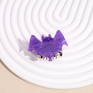 Close-up of a purple glittery bat-shaped hair claw clip on a white display plate