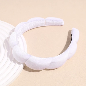 Macro shot of cloud-shaped white sponge headband showing soft knitted texture and padded design