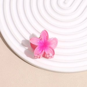Detail view of a pink gradient plumeria hair claw clip with a glossy resin finish