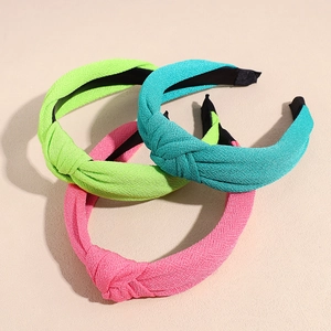 Three-piece set of knotted fabric headbands in green, blue, and pink with textured fabric