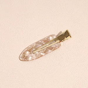 Dettaglio del fermaglio per capelli a scacchi in acetato con clip in metallo dorato in primo piano