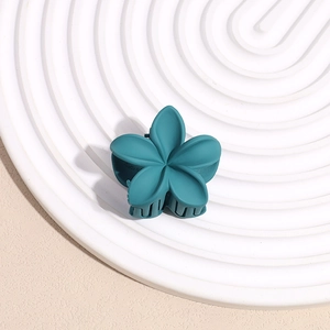Gros plan d'une pince à cheveux fleur bleu foncé mat sur un fond texturé élégant