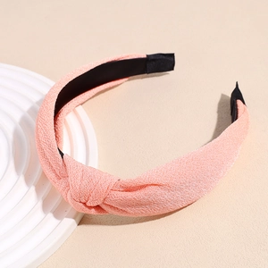 Detail of pink knotted fabric headband on white spiral stand with soft texture