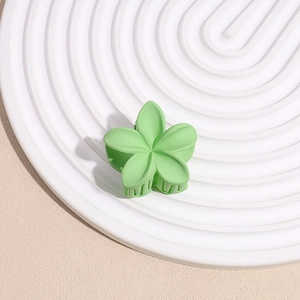 Détail d'une pince à cheveux fleur vert clair mat avec une structure à dents précise