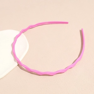Close-up of pink wavy thin headband with non-slip teeth on a textured background