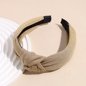 Macro detail of gold knot headband featuring shimmering metallic fabric and anti-slip lining