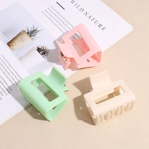 Three minimalist matte square shark clips in pastel pink mint green and cream on a desk