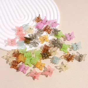Bunte Mini-Schmetterlings-Haarklammern in Bonbonfarben auf einer weiß strukturierten Platte