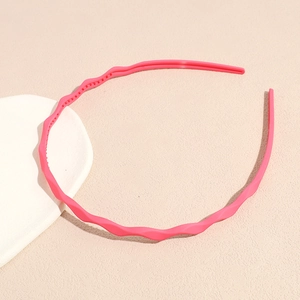 Detail of bright pink wavy hairband with non-slip teeth on a neutral background