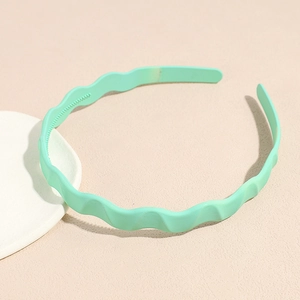 Detail view of mint green wavy headband with anti-slip teeth on a textured surface