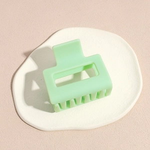 Modern mint green matte square hair claw clip placed on a white ceramic plate