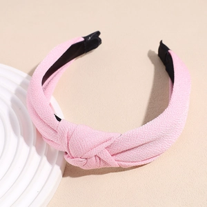 Detail view of the pink fabric texture and cross knot design on a minimalist headband