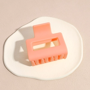 Close-up of small matte peach square hair claw clip on a textured stone surface
