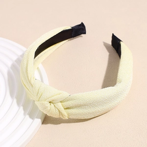 Detail of light yellow knotted headband showing knit fabric texture and black inner lining