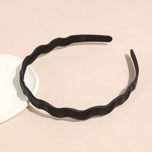 Close-up of matte black wavy headband featuring non-slip inner teeth on ceramic plate