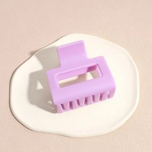 Macro view of light purple matte square hair claw clip on a decorative white plate