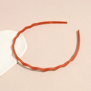 Detailed close-up of orange wavy headband with inner teeth and matte frosted texture