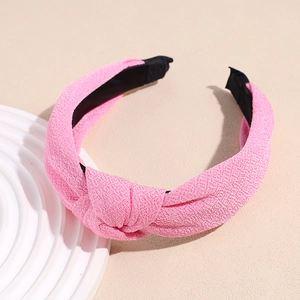 Detail of pink knotted fabric headband with textured crepe weave on a geometric display