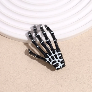 Détail d'une pince à cheveux main de squelette noire avec détails d'os blancs pour Halloween