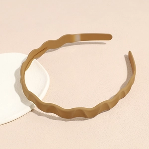 Detail showing wave-shaped khaki matte headband with non-slip inner teeth on stone