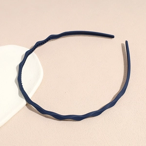 Detail view of dark blue wavy headband with anti-slip inner teeth on beige texture