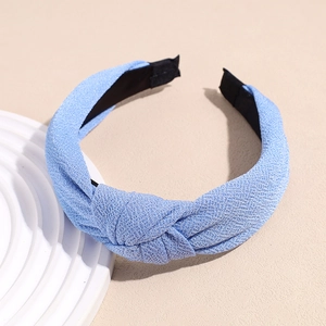 Detail showing light blue knitted fabric texture and top knot design on a wide headband