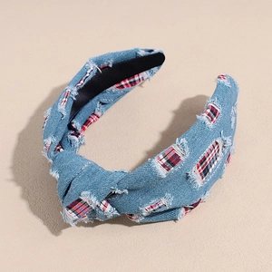 Close-up of blue denim wide headband with plaid fabric patches and frayed edges