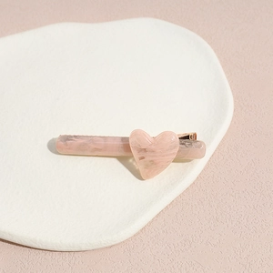 Détail d'une pince à cheveux cœur rose marbré posée sur un plateau blanc