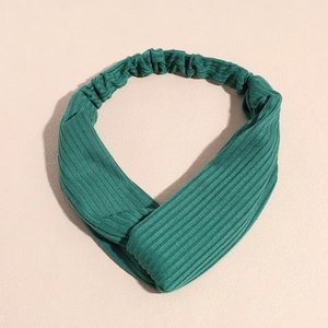 Détail d'un bandeau en maille côtelée vert foncé avec design croisé et bande élastique