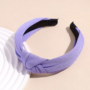 Detail of purple knotted headband showing textured crepe fabric and non-slip lining