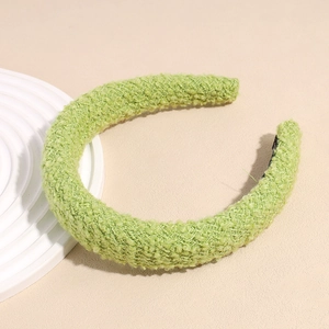 Détail d'un serre-tête vert clair pelucheux montrant sa texture et sa doublure
