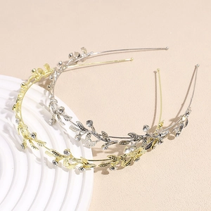 Elegant gold and silver leaf headband with crystals on a minimalist display stand