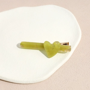 Vue détaillée d'une barrette cœur vert sauge avec texture marbrée et pince dorée