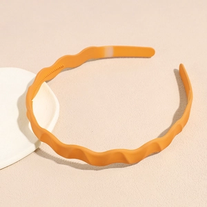 Close-up of bright orange wavy headband featuring non-slip teeth for secure grip