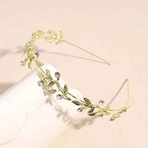 Detail of golden metal headband featuring intricate leaf patterns and sparkling rhinestones