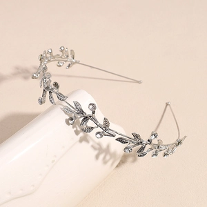Detailed view of silver leaf vine headpiece with sparkling crystals on a ceramic stand