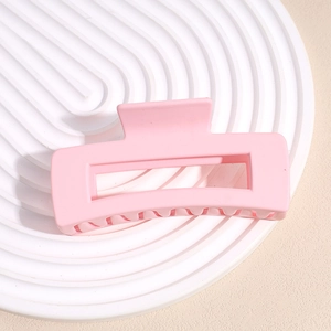 Detail view of large matte pink rectangular hair claw clip on a white round tray