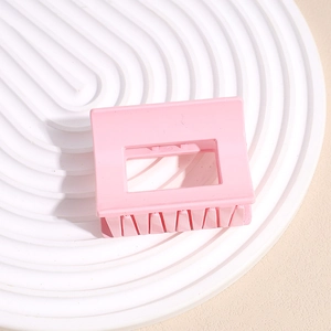 Macro view of matte pink rectangular hair claw clip with interlocking teeth on waves