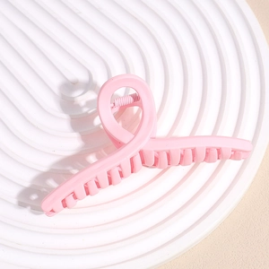 Top view of matte pink large hair claw clip with twisted design on white spiral base