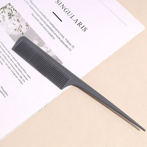 Detail shot of a professional charcoal grey parting comb with fine teeth on a magazine