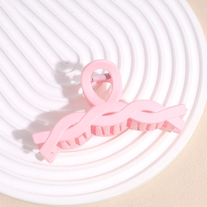 Detailed macro view of a large pink matte shark hair claw clip on a white pedestal