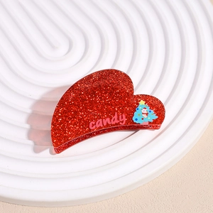 Détail d'une pince à cheveux coeur rouge pailleté avec texte candy et motif sapin Noël
