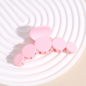 Macro shot of large pink matte shark hair clip with round modular design on white tray