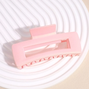 Macro detail of a large pink rectangular hair claw clip with a matte pearl finish
